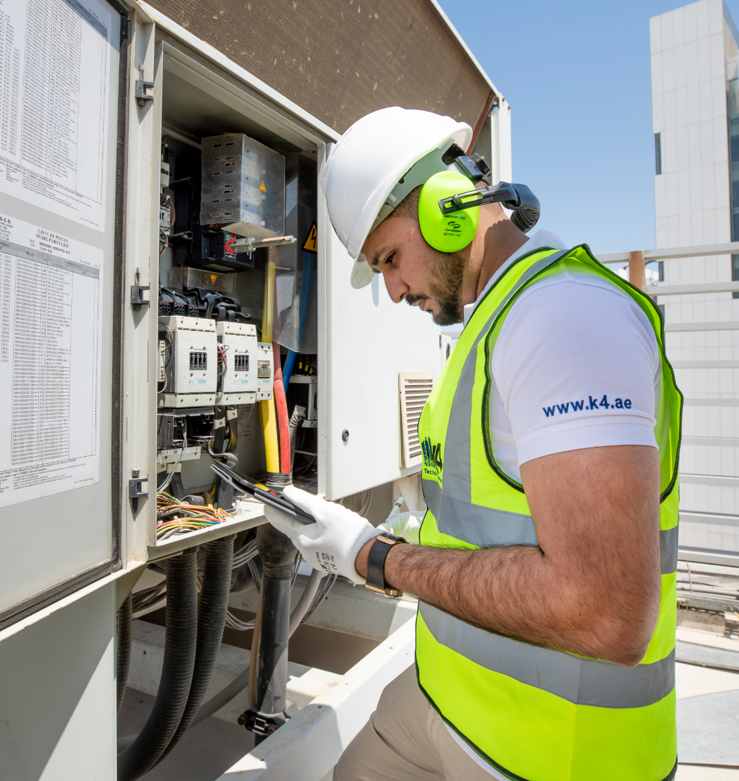 K4 technician servicing an electrical panel on a rooftop in Dubai