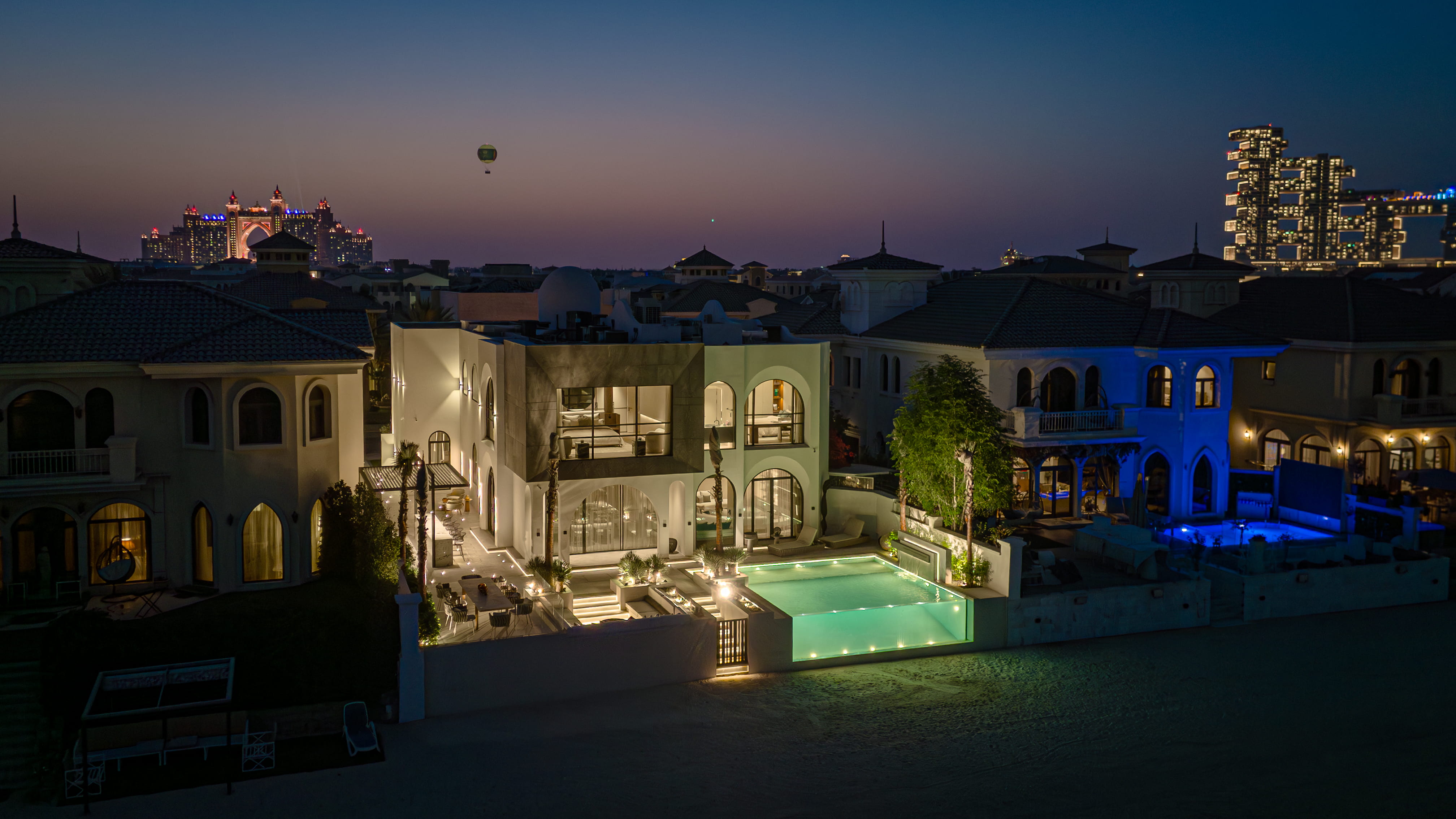 Illuminated Palm Jumeirah beachfront villa at twilight